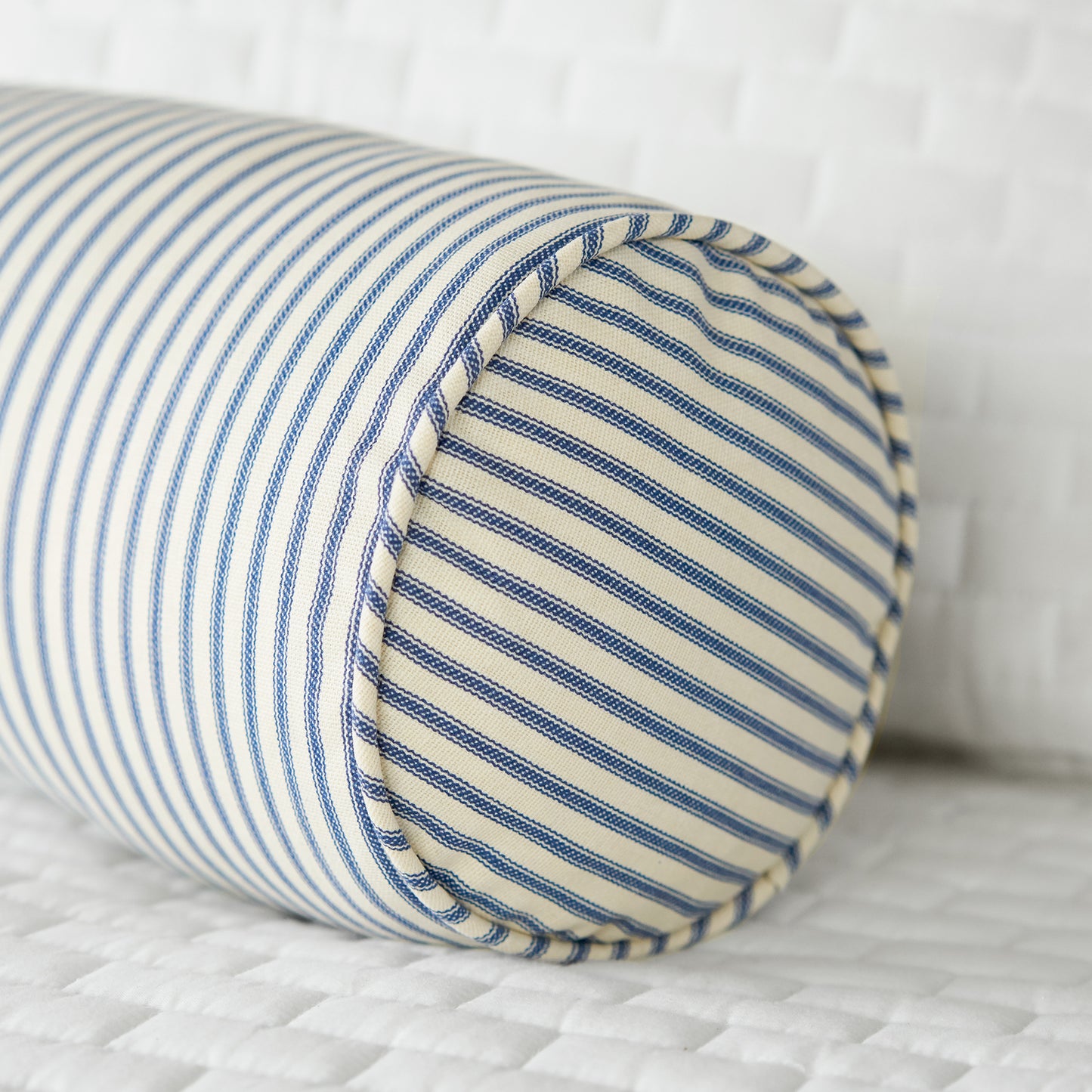 blue ticking stripe bolster pillow on bed