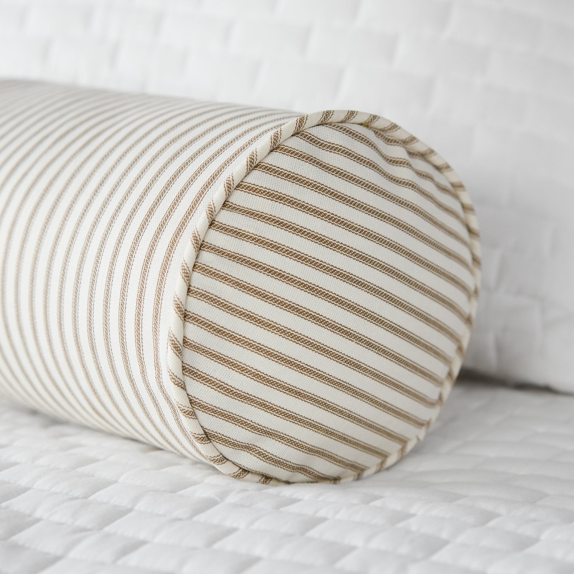 brown ticking stripe bolster pillow on bed