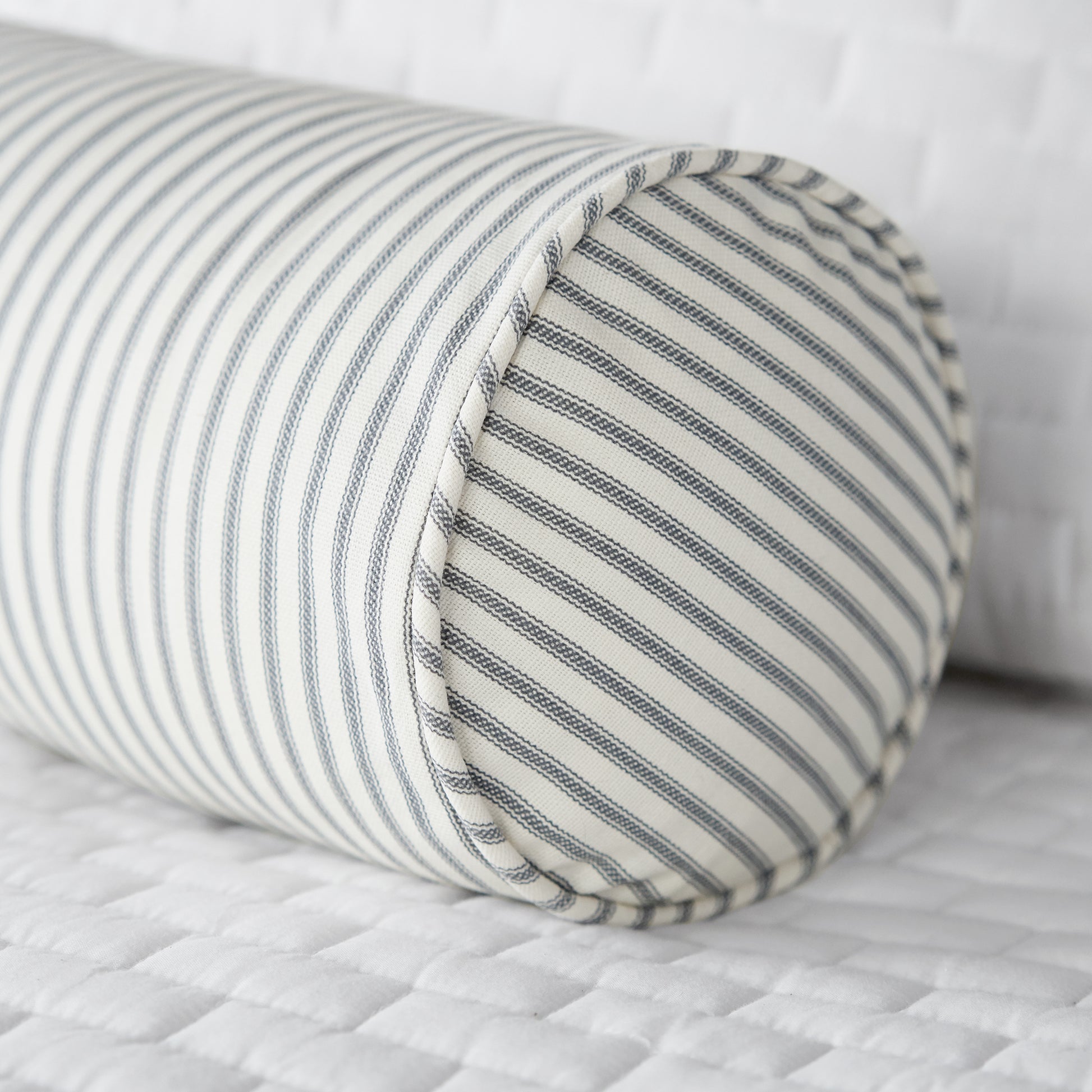 gray ticking stripe bolster pillow on bed