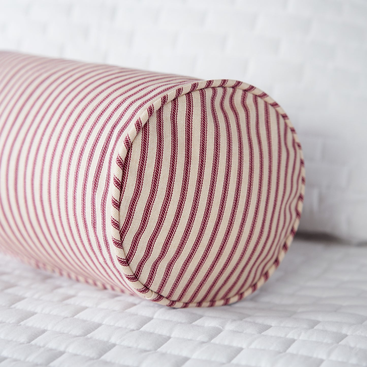 red ticking stripe bolster pillow on bed