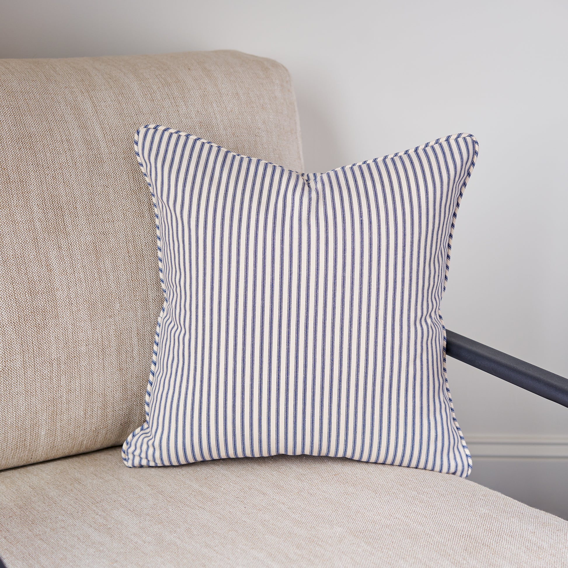 blue and cream ticking stripe throw pillow in chair